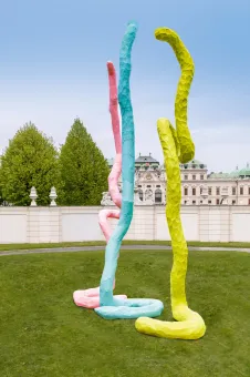 drei Skulpturen von FRanz West in rosa, blau und gelb, im Hintergrund das Obere Belvedere