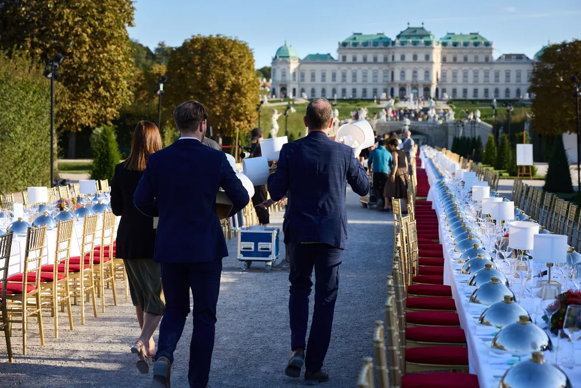 Mitarbeiter von hinten gesehen bei der Dekoration einer langen Tafel im Park.