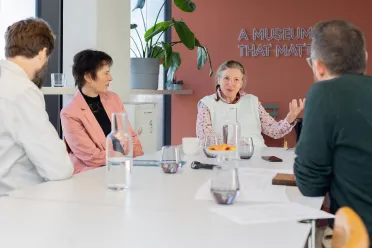Personen sitzen an einem Bürotisch und diskutieren
