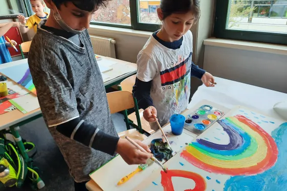 Kinder malen ein Regenbogenbild