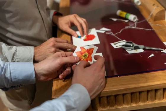 Zwei Personen bei einem Collagen Workshop mit ausgeschnittenen Fotografien in der Hand