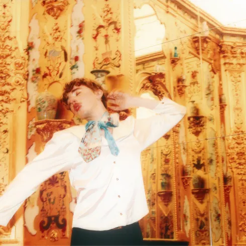 The musician Oskar Haag dancing before a gilded wall.