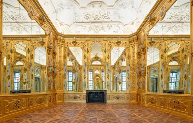 Eine Raumansicht. Die Wände sind mit großen Spiegeln und flächendeckend mit Blattgold verkleidet.