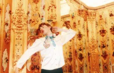 The musician Oskar Haag dancing before a gilded wall.