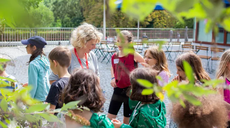 Kunstvermittler*in mit einer Schulklasse im Skulpturengarten des Belvedere 21